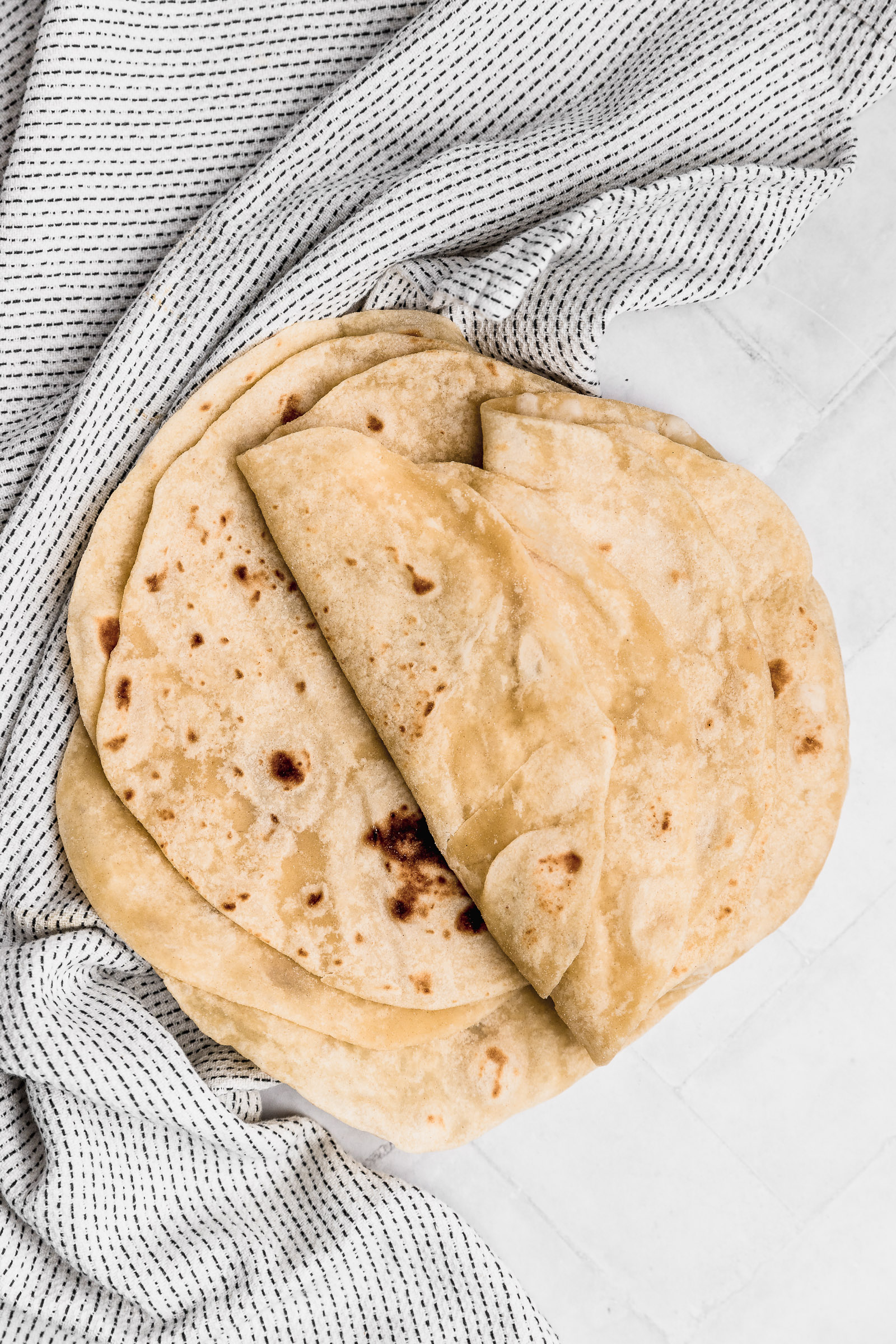 tortillas de harina caseras y suavecitas montadas una sobre otra, la mitad dobladas en dos